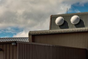 Metal building with pronounced panel design against a cloudy sky