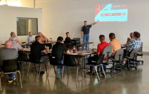 Metallic Products' owner and president Travis Wendt speaks to a group of people at a lunch and learn, in a photo illustrating a blog post about how the company shapes the steel building industry