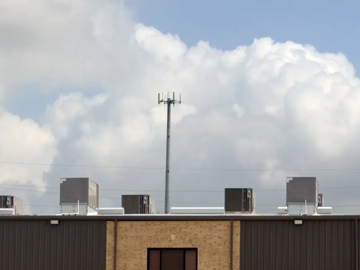 Roof-mounted equipment on Metallic Products roof curbs atop a steel building, against a cloudy blue sky